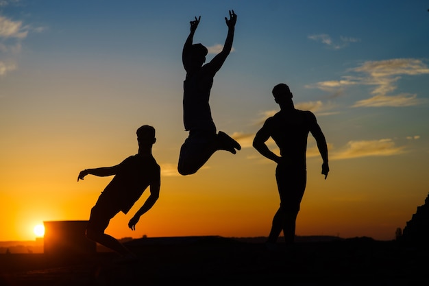 Premium Photo | Group of happy young people jumping on the roof with sunset