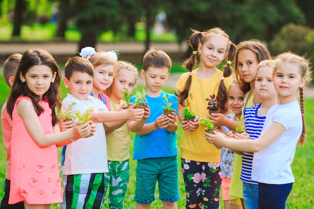 Group of kids holding plants in flowerpots Premium Photo