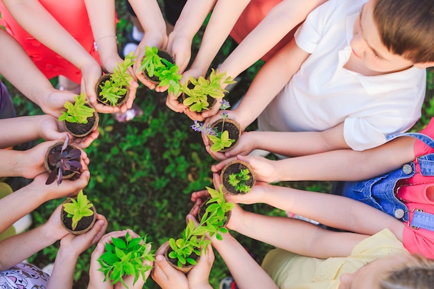 Group of kids holding plants in flowerpots Premium Photo