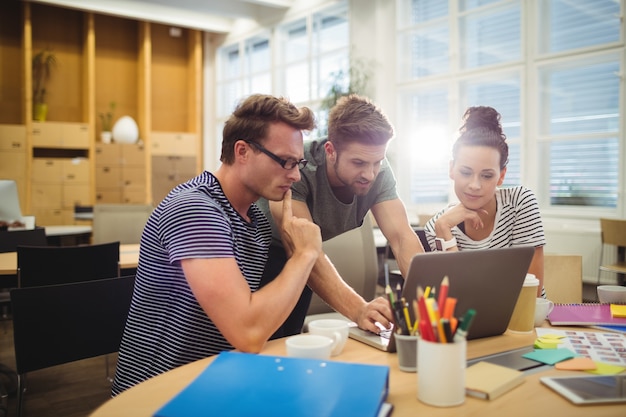 Group of graphic designers discussing over laptop at their desk  Photo | Free Download