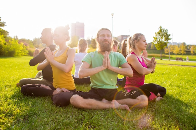 Premium Photo | A group of people in a lotus pose on a green lawn in ...