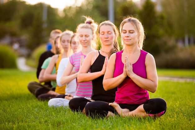 Premium Photo | A group of people in a lotus pose on a green lawn in ...