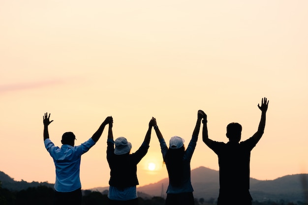 Premium Photo | Group of people with raised arms looking at sunrise on ...