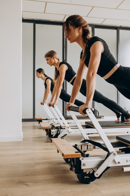 Free Photo | Group of pilates instructors exercising on reformers