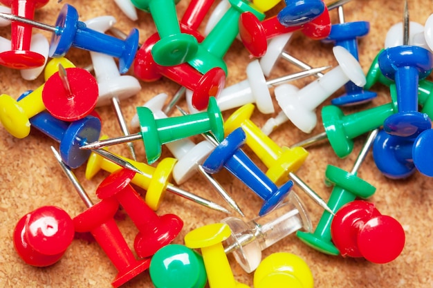 Premium Photo | Group of thumbtacks on corkboard close up.