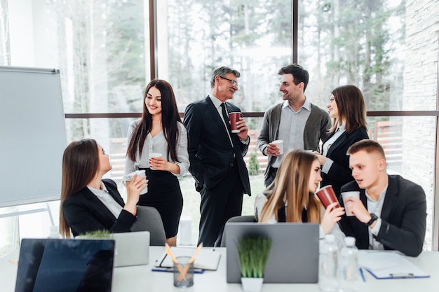 Group of young business people on break in office. successful business team  talking on coffee break. young smiling colleagues on break drinking coffee  chatting in modern office. corporate lifestyle | Premium Photo