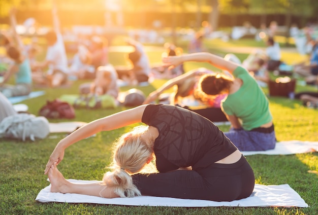 A group of young people do yoga in the park at sunset. Premium Photo