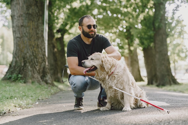 盲導犬が市内の盲人を助ける ハンサムな盲目の男は 街でゴールデン リトリーバーと残りを持っています 無料の写真