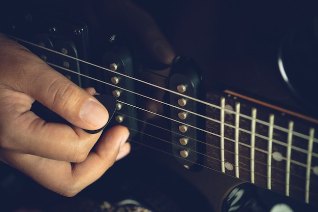 Premium Photo Guitarist Is Rehearsing Playing Black Vintage Electric Guitars Closeup Hand Is Holding The Pick And Putting It On Guitar String