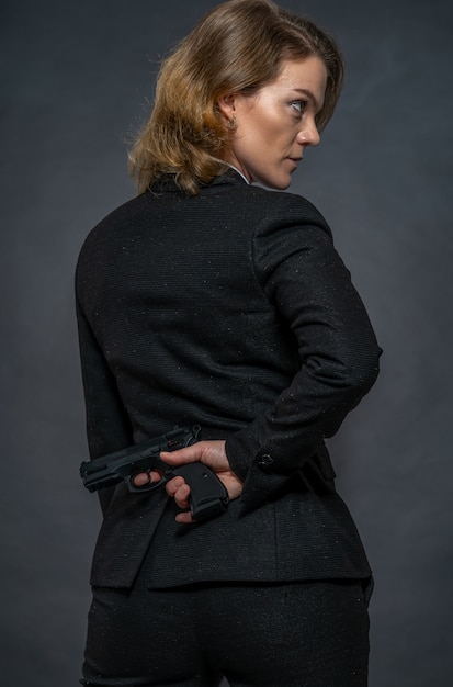 スーツを着た女性の背中の後ろに手に銃 プレミアム写真