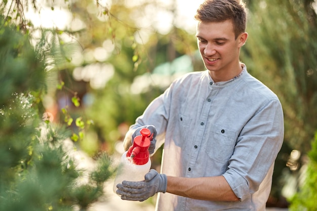 Premium Photo | Guy gardener sprays water on plants in the beautiful ...