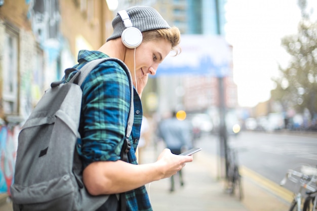 Парень слушает музыку в наушниках во время прогулки по улице | Премиум Фото