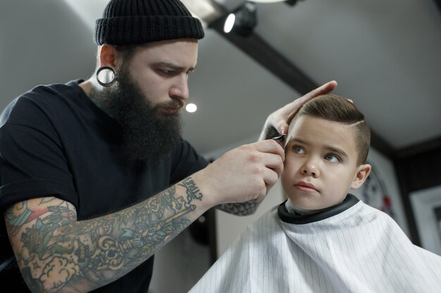美容師が小さな男の子の髪をカット 無料の写真