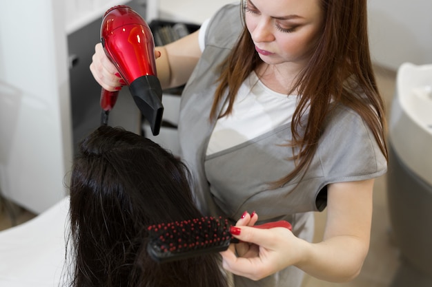 Premium Photo | Hairdresser dries wet hair girl with a hair dryer