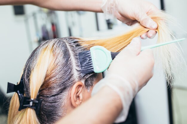 Premium Photo | Hairdresser is dying hair roots of young woman.