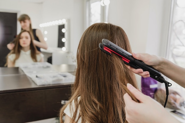 Premium Photo | A hairdresser makes a hairstyle for a girl in a beauty ...