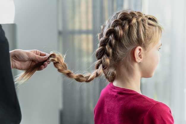 Premium Photo Hairdresser Weaves A Braid To A Preteen Blond Girl In A Beauty And Hair Salon