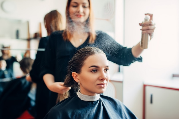 美容師はヘアスプレー 美容院の女性クライアントで動作します プレミアム写真