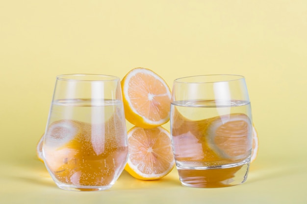 Free Photo Half Lemons And Water Glasses On Yellow Background