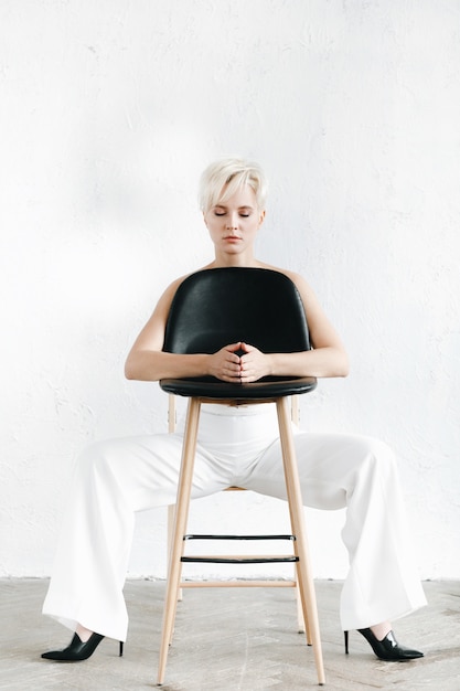 白いズボンの半裸のモデルが黒い椅子に座っている 無料の写真