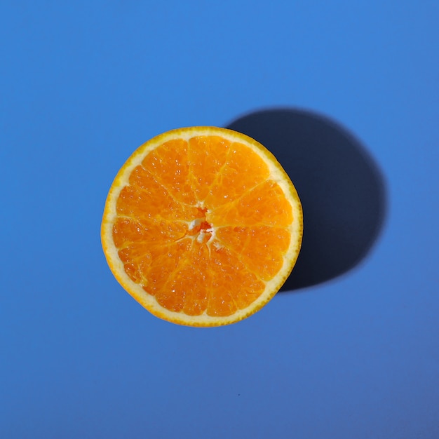 Half an orange with a blue background Photo | Premium Download