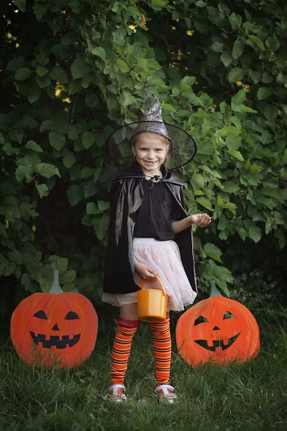 Premium Photo | Halloween little girl dressed in witch costume holds ...