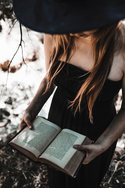 Free Photo | Halloween witch holding antique spellbook in sunlit woods