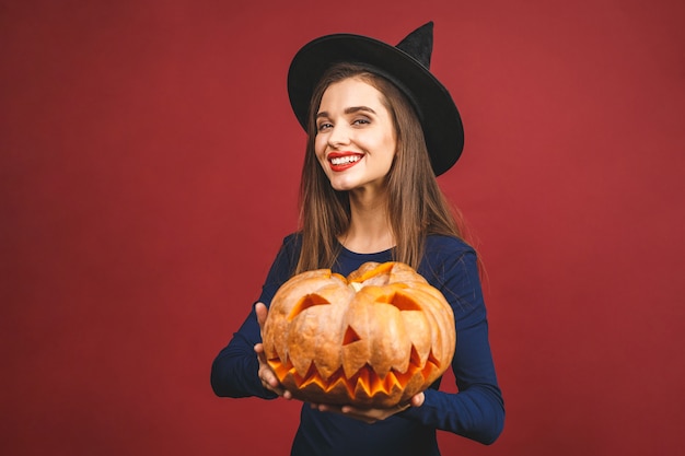 Premium Photo | Halloween witch with a carved pumpkin - isolated on red ...
