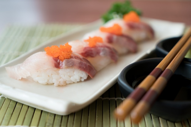 Hamachi Sushi On White Plate Along With Japanese Sauce And Green