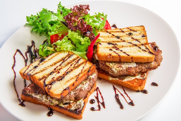 Hamburger closeup with bacon and cheese sauce, salad, olive dressing Free Photo