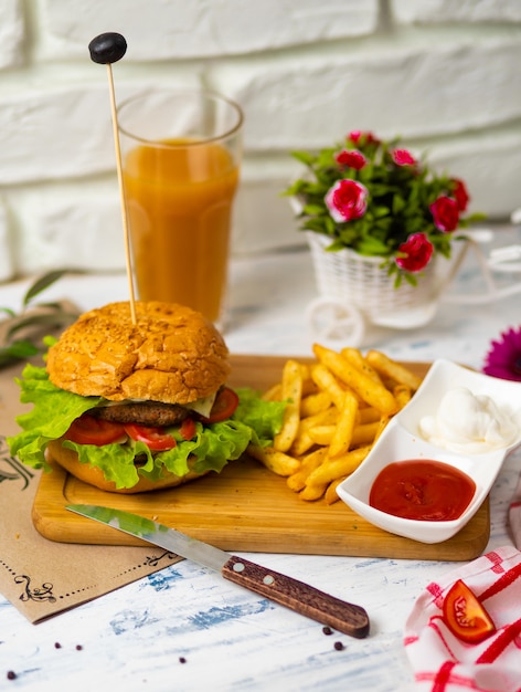 Hamburger with french fries on wooden board with ketchup and mayonnaise, kitchen Free Photo
