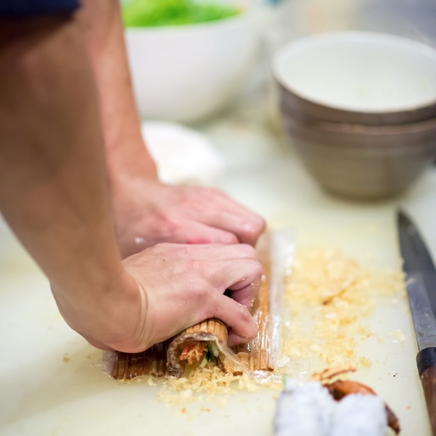 Premium Photo | Hand of chef making of sushi rolls