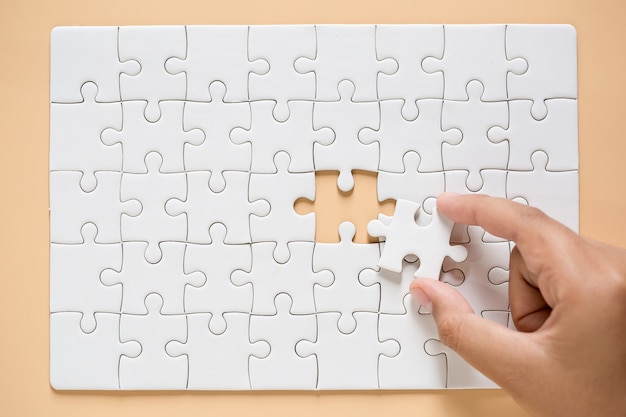 Free Photo | Hand connecting puzzle pieces on table background