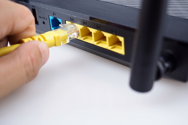 Hand connecting a yellow network cable on a lan port of a router ...