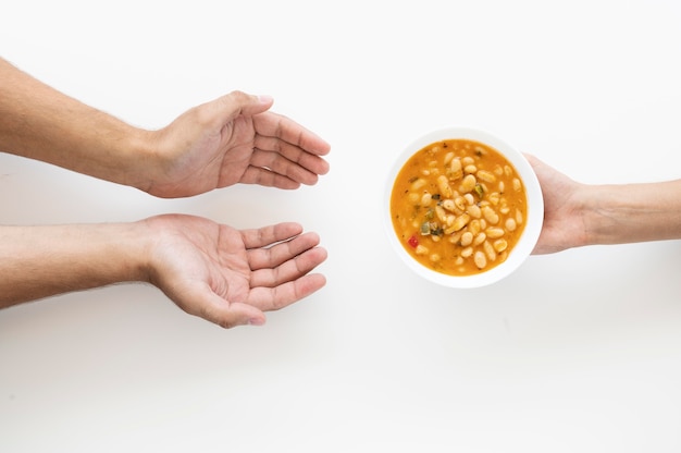 Free Photo | Hand giving soup bowl to needy person