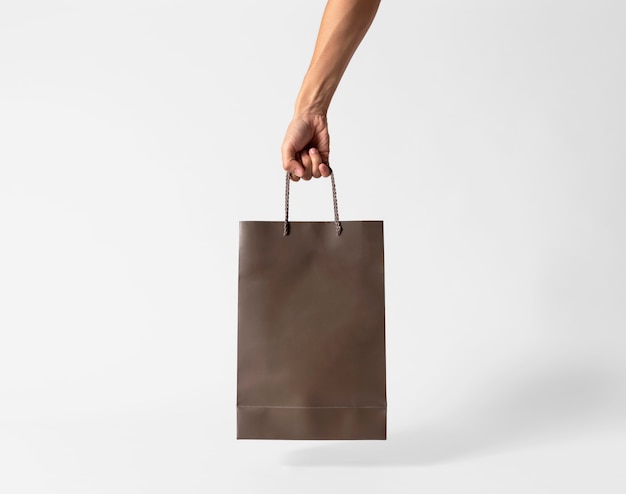 Download Hand holding blank brown paper bag for mockup template advertising and branding on gray ...