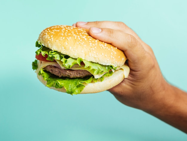 Free Photo | Hand holding delicious burger with blue background