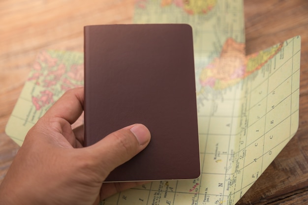 hand holding passport with map world 1232 1125 - Ketahui 3 Jenis Paspor di Indonesia dan Kegunaannya