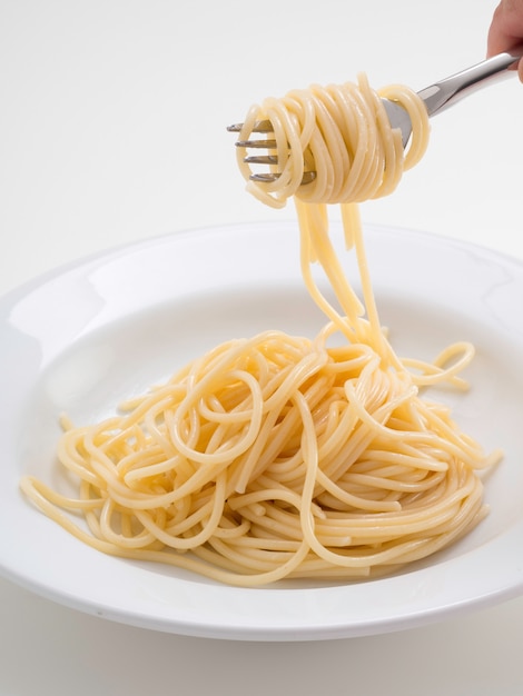 Premium Photo Hand Holding Roll Pasta Spaghetti With A Fork And Bish 4032