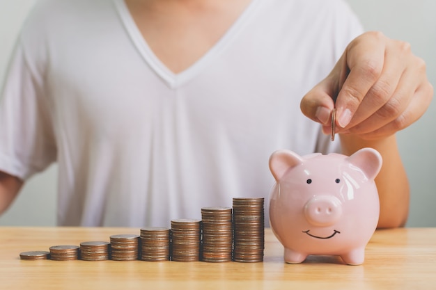 Premium Photo | Hand of male putting coins in piggy bank with money stack step growing growth saving money