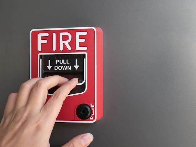 Premium Photo | The hand of man pulling red fire alarm on gray background