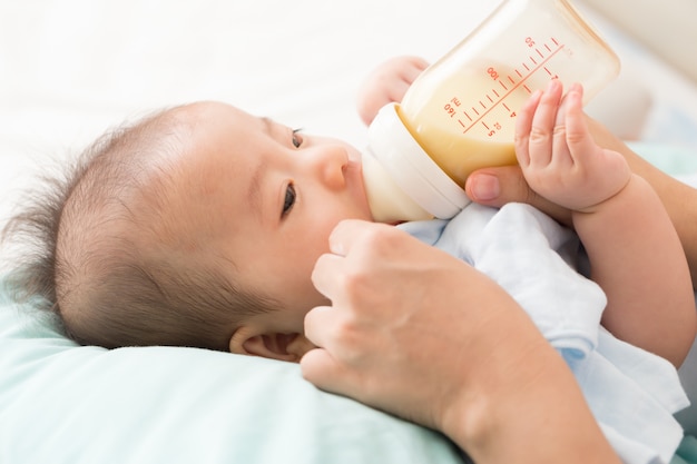 Hand of mother feeding baby with milk bottle Premium Photo