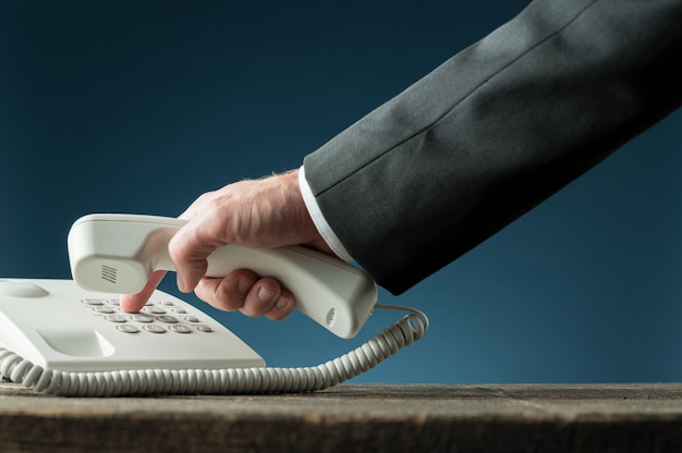 電話番号をダイヤルする電話の受話器を持っているビジネスマンの手 プレミアム写真