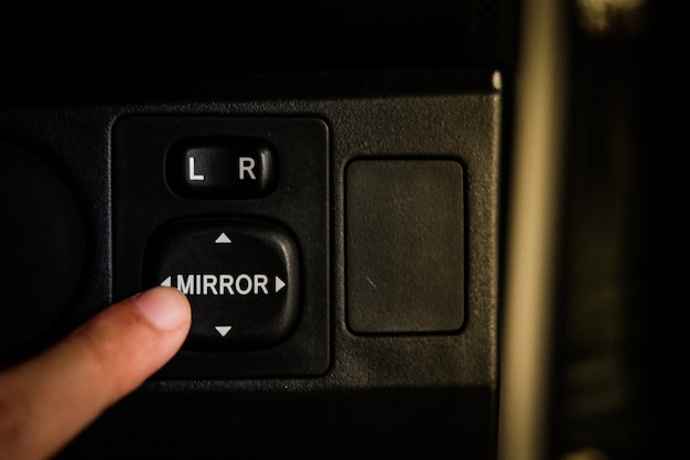 サイドミラーを調整するためのボタンミラーを押すドライバーの手 プレミアム写真