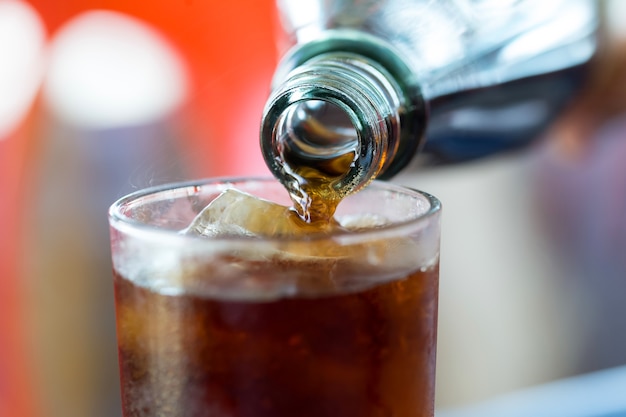 Premium Photo | Hand pouring coke bottle glasses.