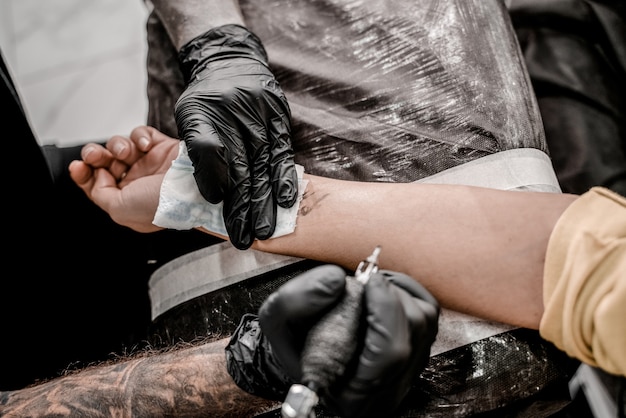 Premium Photo | Hand of professional artist wiping finished tattoo with