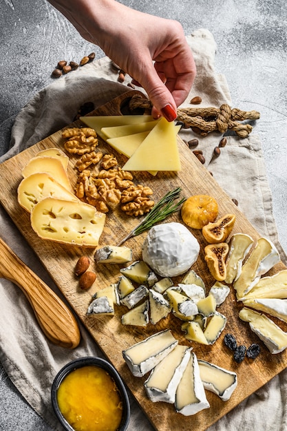 Premium Photo | Hand takes a piece of cheese from a cheese plate served ...