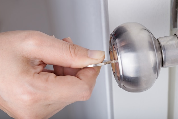 Hand Use The Key For Unlocking Door Knob On White Door Photo