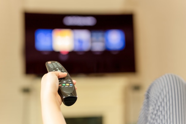 Premium Photo | Hand using remote controller for watching television at ...