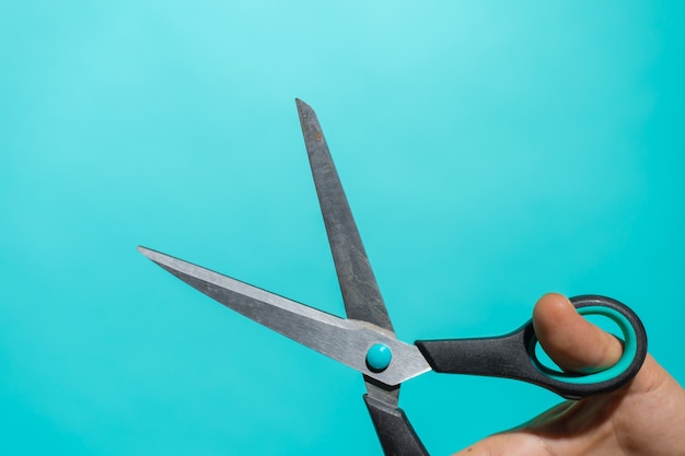 Premium Photo | Hand with colorful pair of scissors in front of a blue ...